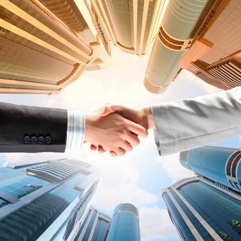 Close up image of hand shake against skyscrapers