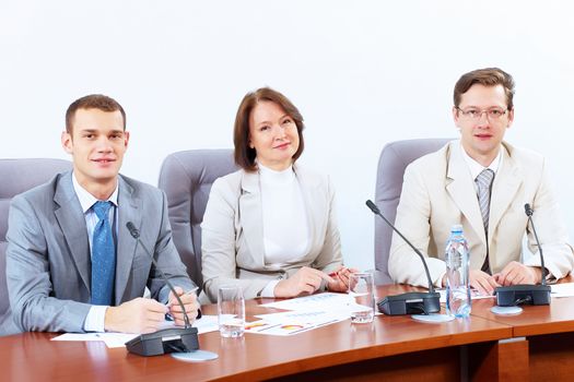 Image of three businesspeople sitting at table at conference