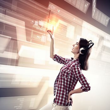 Image of young woman with headphones touching virtual screen