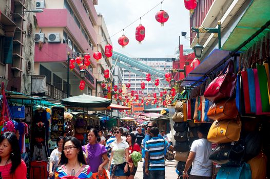 Kuala Lumpur, Malaysia - May 11, 2012: People walking on Petaling Street in Kuala Lumpur. The street is a long market which specializes in counterfeit clothes, watches and shoes. Famous tourist attraction