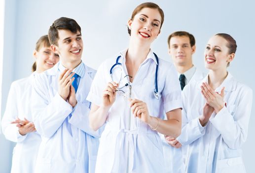 successful doctor, accepts congratulations from colleagues, stand behind him and clap