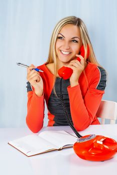 beautiful smiling female holding phone and ballpoint pen