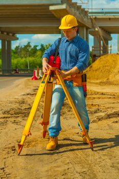 construction worker adjusting theodolite