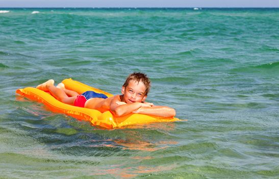 Happy boy enjoying summer day floating in the sea