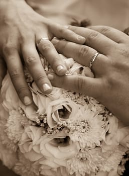 A couple's hands with wedding rings on a bouquet