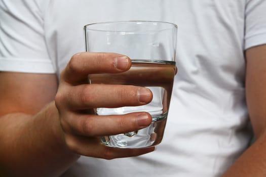 Man's hand holding a glass of clean filtered water