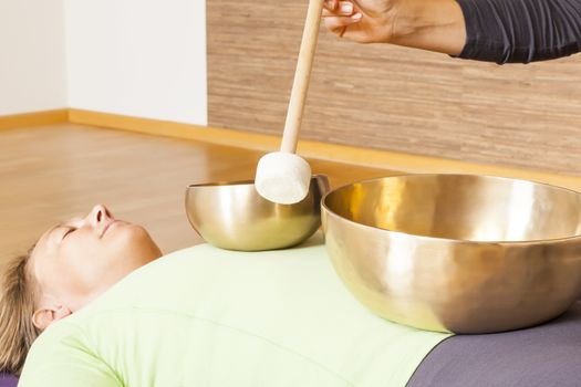 A woman is relaxing with singing bowls on her body