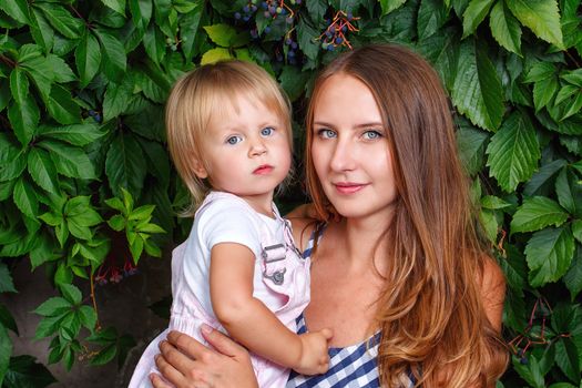 Mother holds daughter on hands on a background of city park