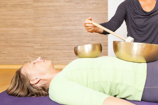 A woman is relaxing with singing bowls on her body