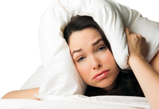 A tired sleepless woman with the pillow over her head . Isolated over white.