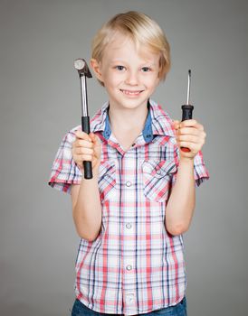 A cute young boy holding a hammer and a screwdriver
