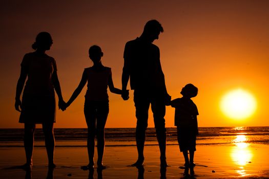 Silhouette of family on the beach at sunset