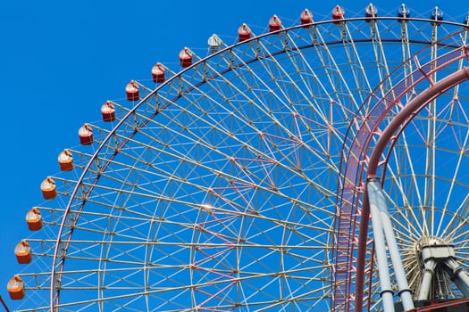 Part of Ferris wheel with blue sky.