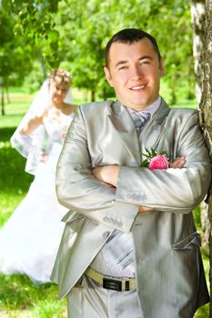 The groom near a tree and the bride on a background