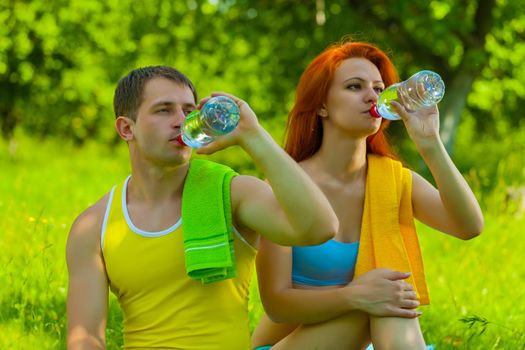 a men and female drinking water from bottles