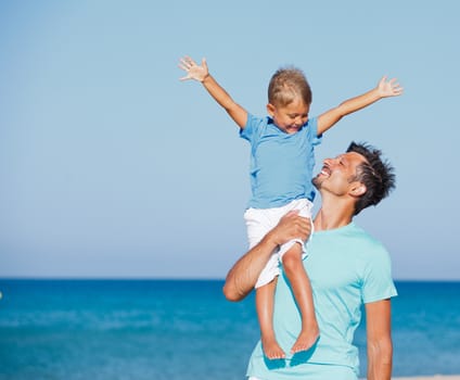 Father and son having fun on tropical white sand beach