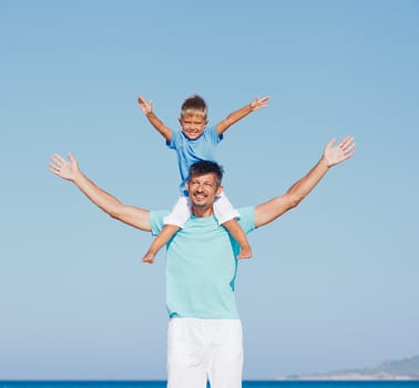 Father and son having fun on tropical white sand beach