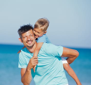 Father and son having fun on tropical white sand beach