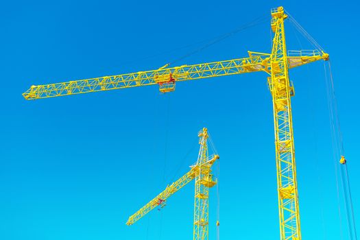 two tops of construction cranes on sky