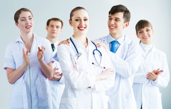 successful doctor, accepts congratulations from colleagues, stand behind him and clap