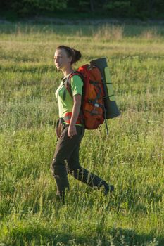 Happy smiling woman in field. Green grass in foreground and clear sky in background.
