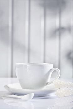white ceramic coffee cup with spoon and sugar sticks