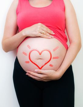 Pregnant woman with the drawn heart on a belly 