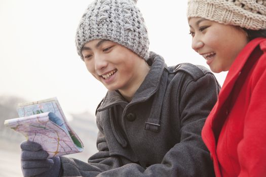 Two young people looking at map outside in winter, Beijing