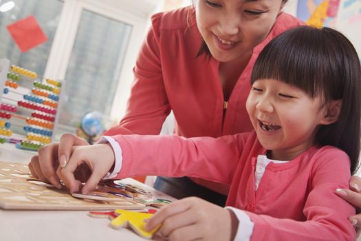 Teacher Helping Young Girl with Cut-Out Alphabet Letters