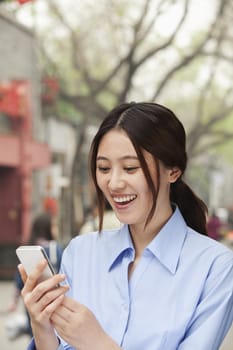 Young Woman smiling and looking mobile phone