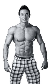 Attractive young muscle man shirtless with checkered shorts smiling, black and white shot