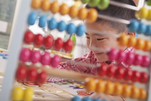 Looking Through Abacus at Boy Solving a Puzzle