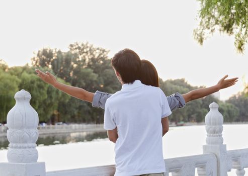 Young Couple with Arms Outstretched by a Lake