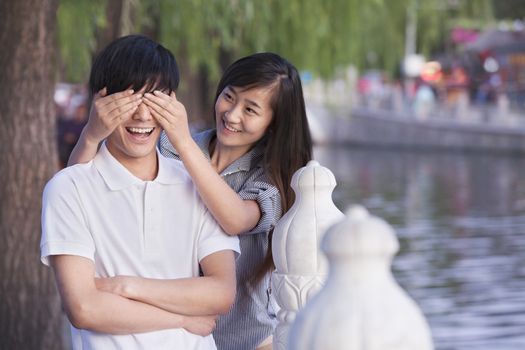 Woman Covering Mans Eyes by a Lake