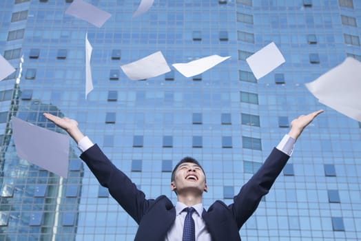 Young Businessman throwing paper with arms in the air