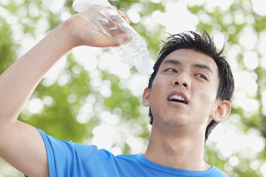 Young Man Drinking Bottled Water in Park