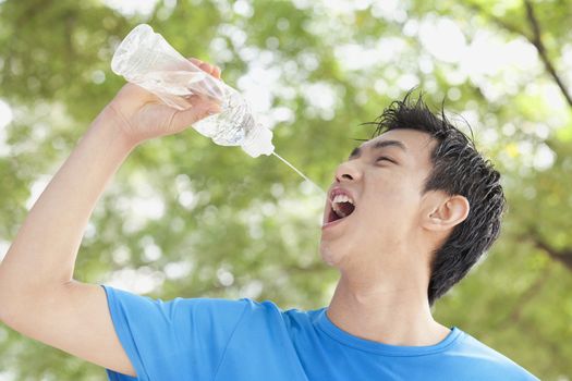 Young Man Drinking Bottled Water in Park