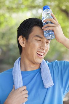 Young Man with Water Bottle after Exercising in Park