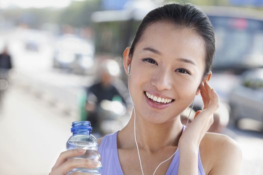 Young Woman with Bottled Water Listening to Music