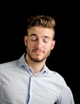 Handsome young man portrait with confident expression, grinning with eyes closed