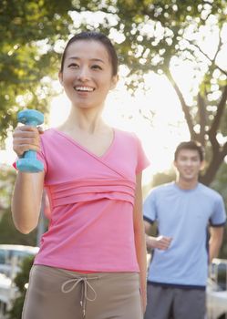 Young Woman Exercising in Park with Dumbells