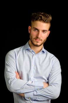 Studio portrait of attractive young businessman looking in camera, on black background