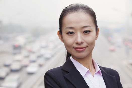 Portrait of Young Businesswoman Looking at Camera with Traffic Below