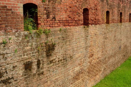 A brick wall with gun portholes in a Civil War era fort, Fort Clinch, which can be seen in Florida at Fort Clinch State Park