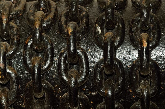 Heavy black iron chains wrapped around a large iron pipe