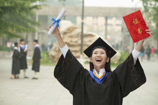 Young Female University Graduate, Arms Raised in the Air with Diploma