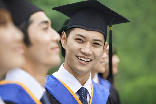 Young Man Smiling in a Row of Young University Graduates