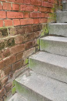 A set of steps along an old red brick wall