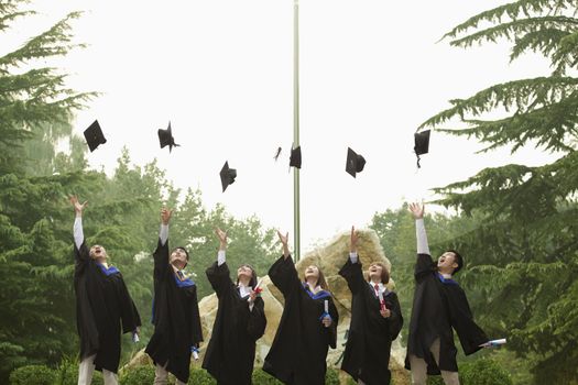 Young Group of University Graduates Throwing Mortarboards in the Air