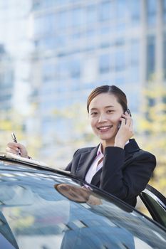 Businesswoman Standing by Car Using Phone, Looking At Camera